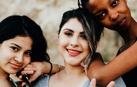 Three women leaning on each other and smiling